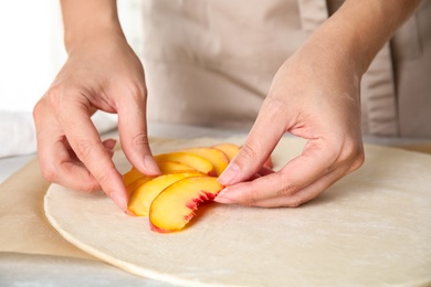 Photo of Woman making peach pie at kitchen table, closeup