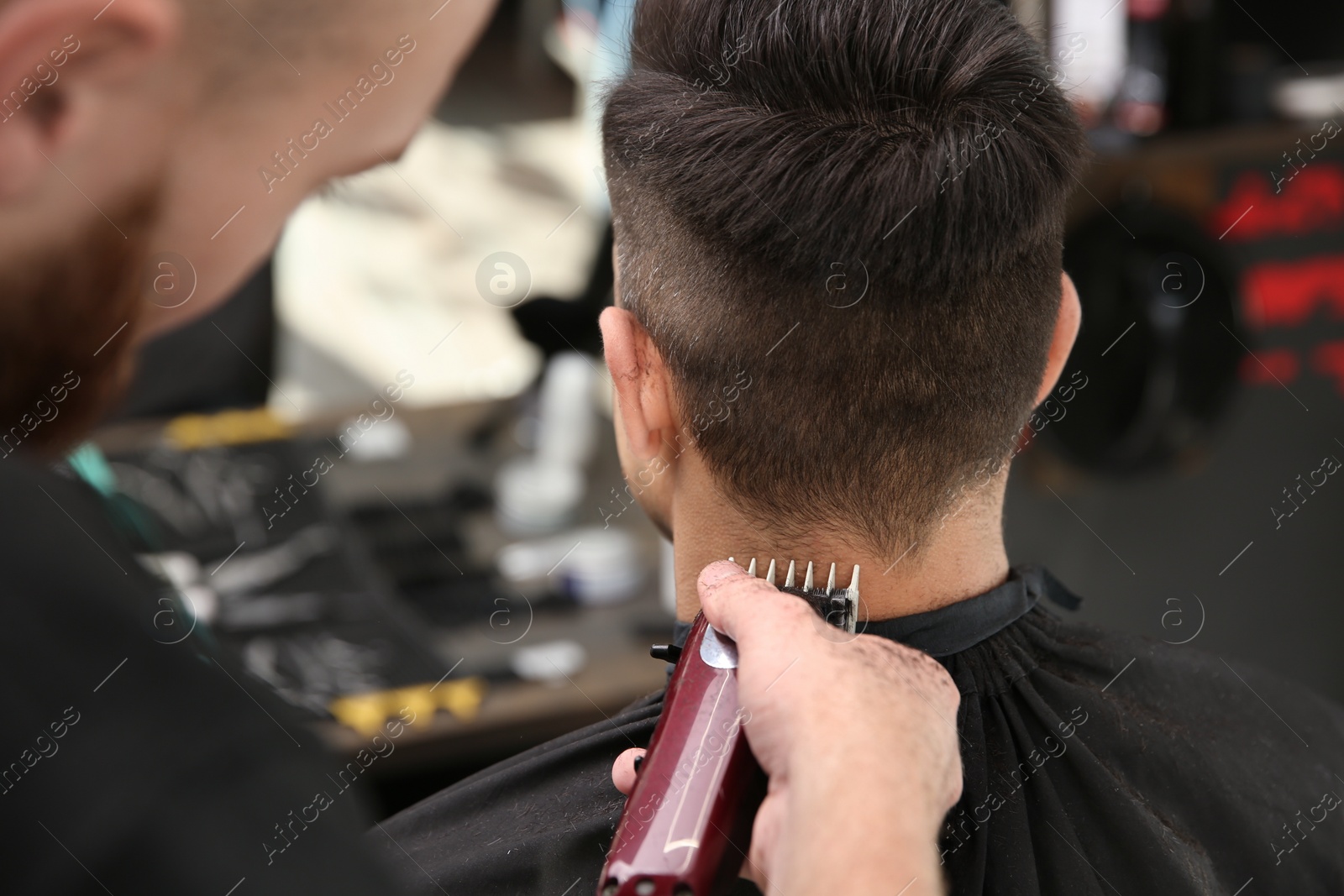 Photo of Professional barber making stylish haircut in salon, closeup