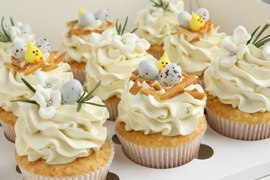 Photo of Tasty Easter cupcakes with vanilla cream in box, closeup