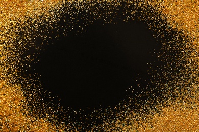 Frame made of gold glitter on black background, top view with space for text