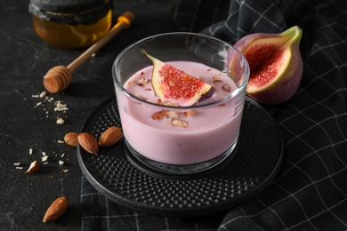 Photo of Delicious fig smoothie in glass on black table