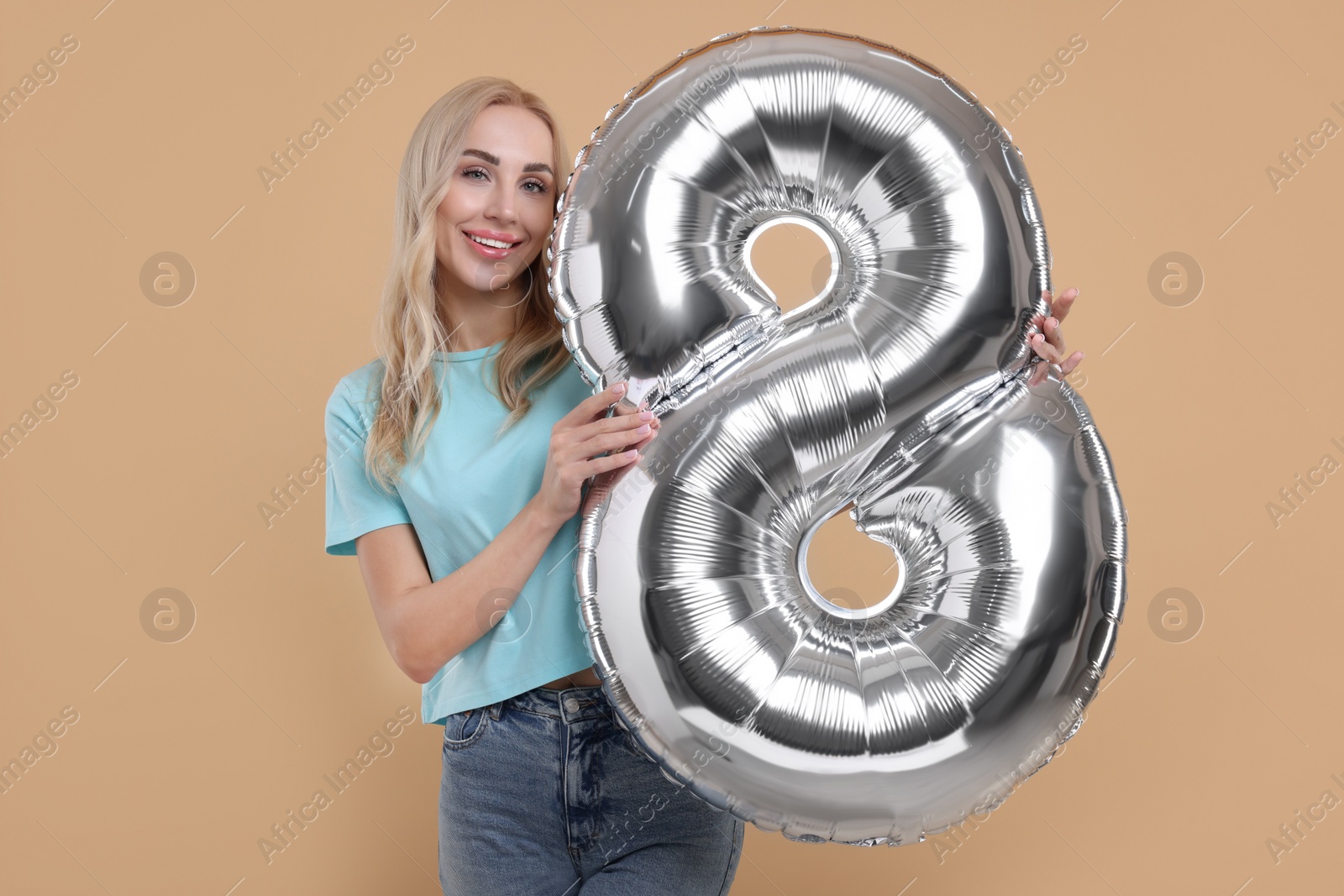 Photo of Happy Women's Day. Charming lady holding balloon in shape of number 8 on beige background