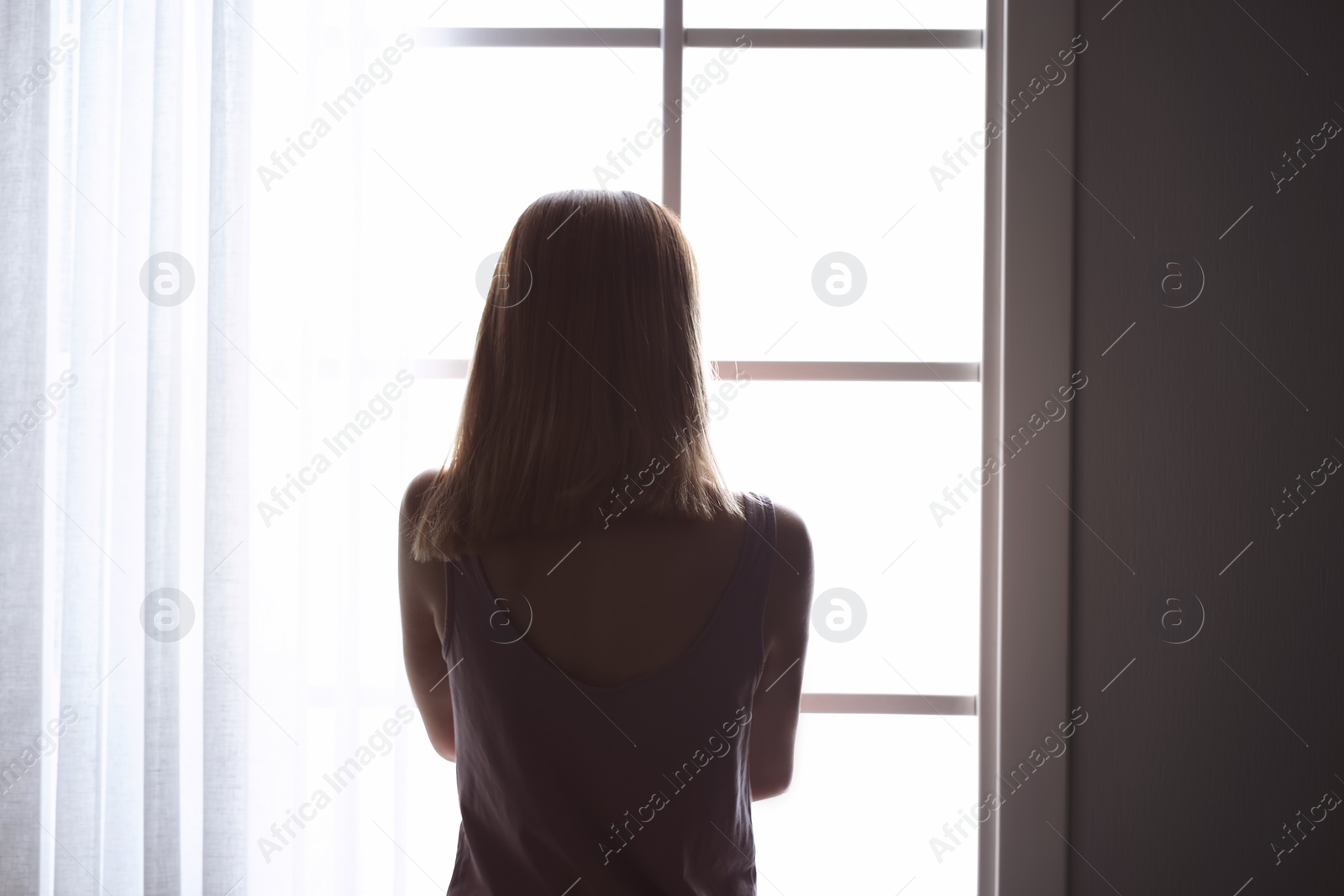 Photo of Lonely woman near window at home. Depression