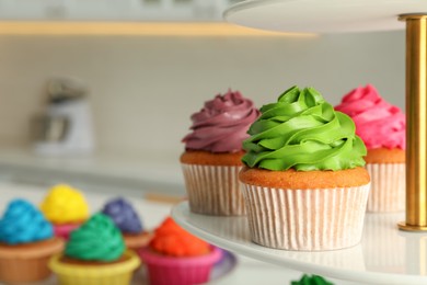 Delicious cupcakes with colorful cream on stand, closeup. Space for text