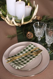 Photo of Christmas place setting with burning candles and other festive decor, closeup