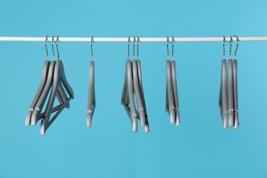 Photo of Metal rack with clothes hangers on color background