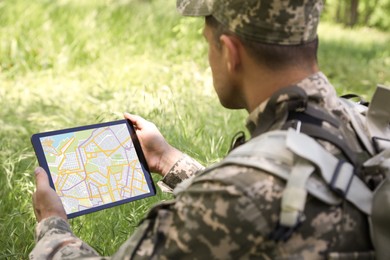 Photo of Soldier with backpack using tablet in forest