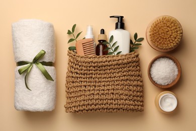 Photo of Preparation for spa. Compact toiletry bag with different cosmetic products, sea salt and towel on beige background, flat lay