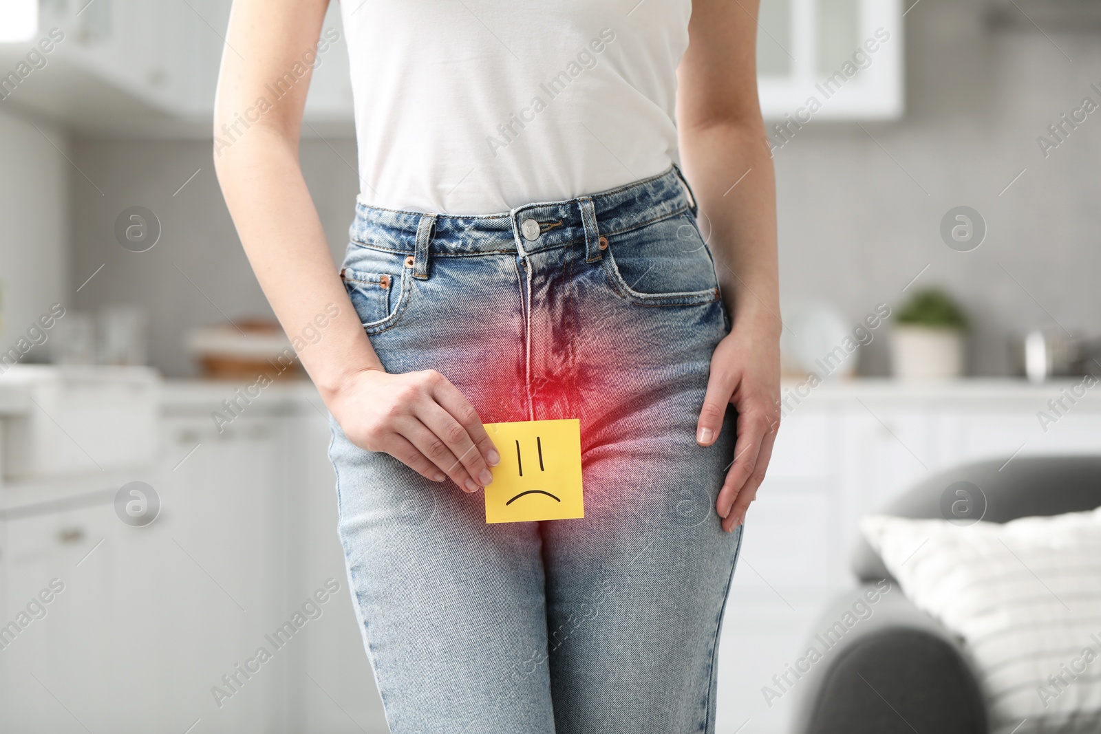 Image of Woman holding sticky note with drawn sad face and suffering from cystitis symptoms indoors, closeup