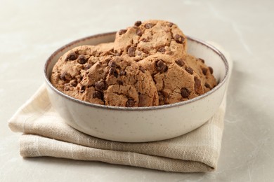 Delicious chocolate chip cookies in bowl on light grey table