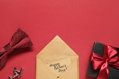 Card with phrase Happy Father's Day, gift box and men accessories on red background, flat lay. Space for text