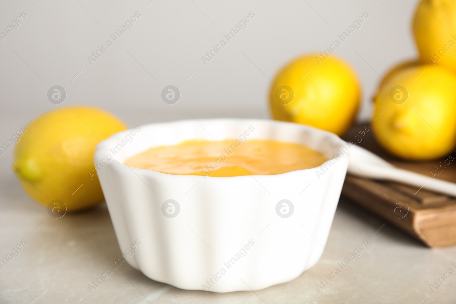 Photo of Delicious lemon curd on light grey marble table