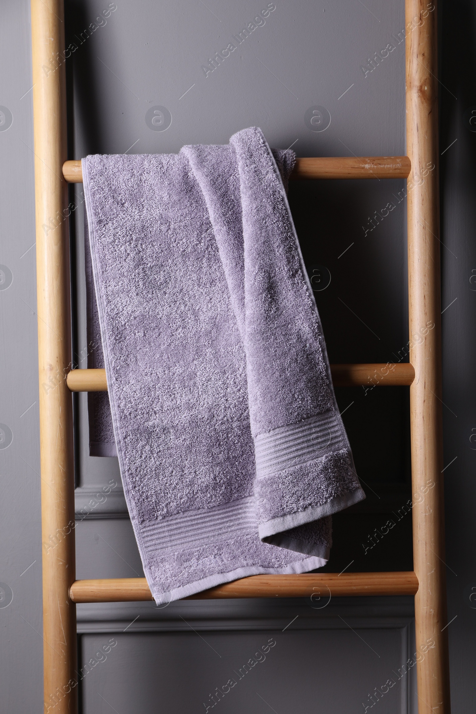 Photo of Soft terry towel on wooden ladder indoors