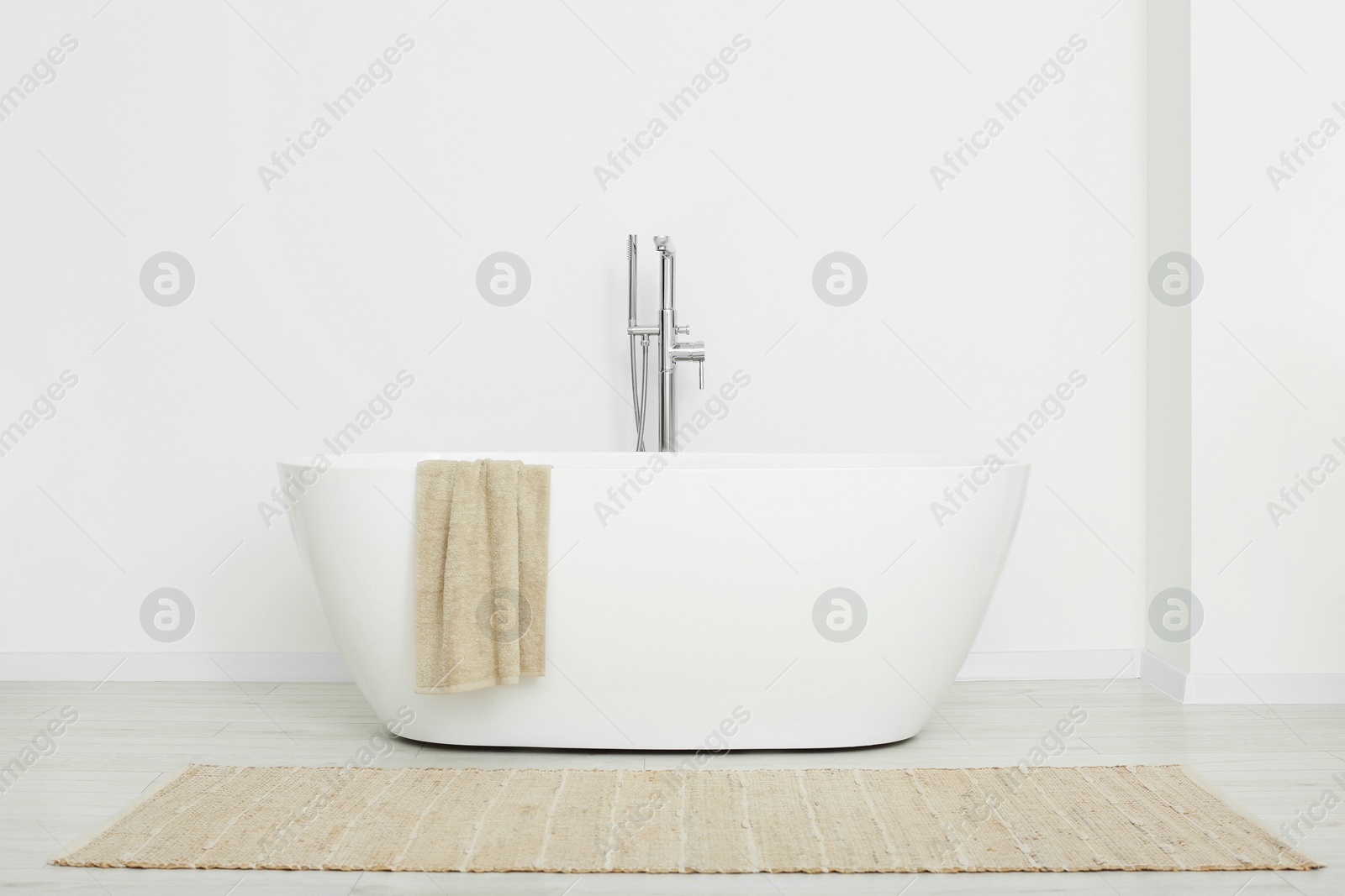 Photo of Beautiful white tub with towel in bathroom. Interior design