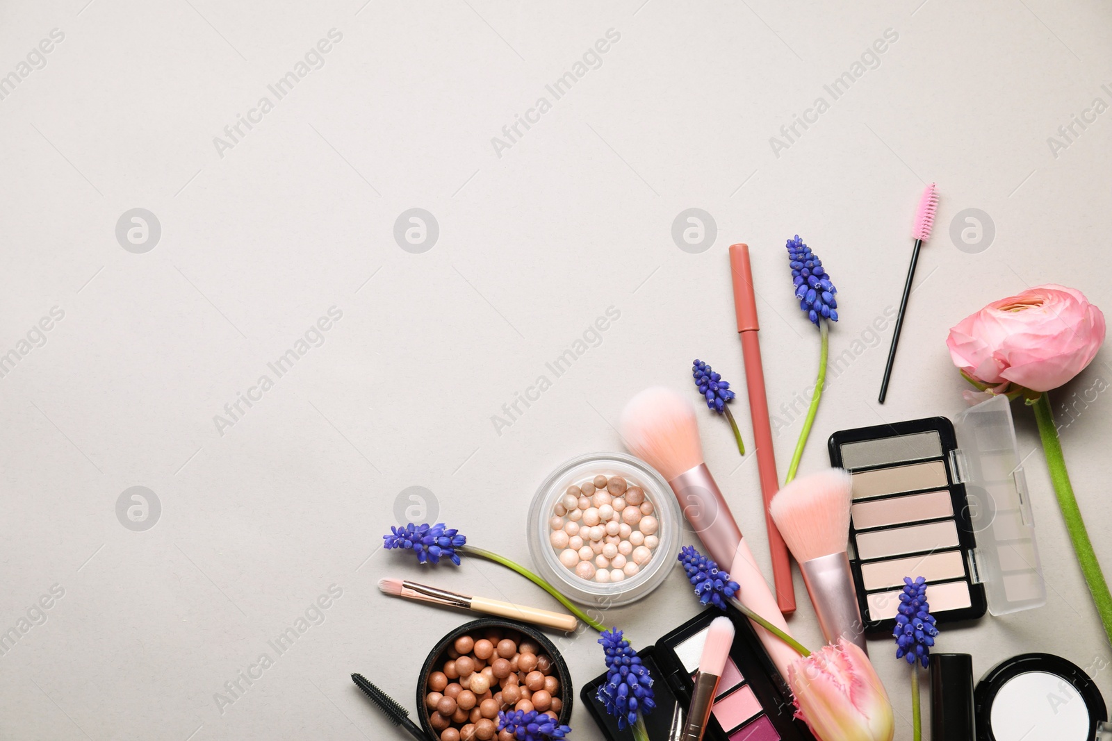 Photo of Flat lay composition with different makeup products and beautiful spring flowers on gray background, space for text