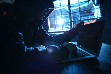 Photo of Hacker with laptop in dark room. Cyber crime