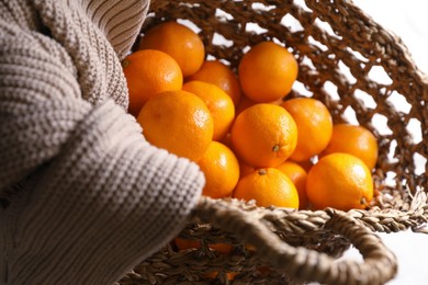 Photo of Net bag with many fresh ripe tangerines on white cloth