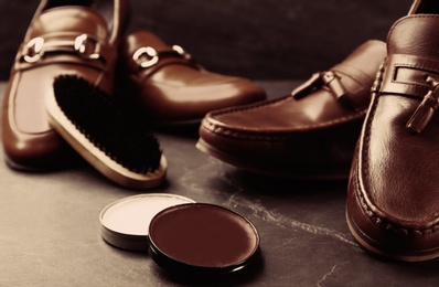 Image of Shoe care accessories and footwear on dark slate background, closeup