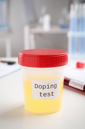 Photo of Jar with urine sample on white table indoors. Doping control