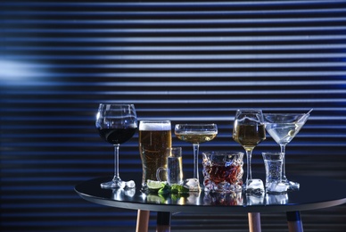 Photo of Many different alcoholic drinks on table against dark background. Space for text