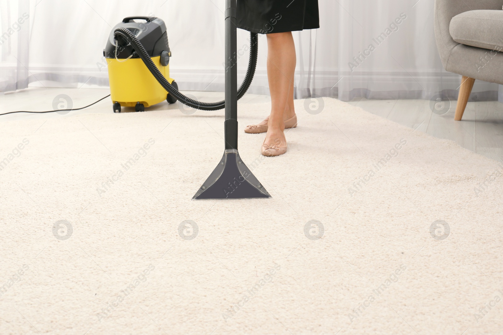 Photo of Woman removing dirt from carpet with vacuum cleaner indoors, closeup. Space for text