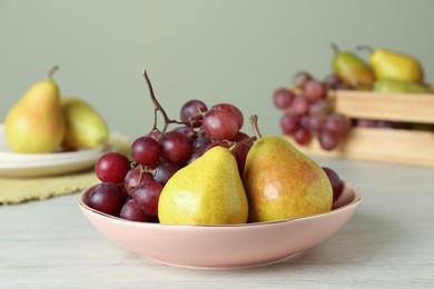 Photo of Fresh ripe grapes and pears on white wooden table
