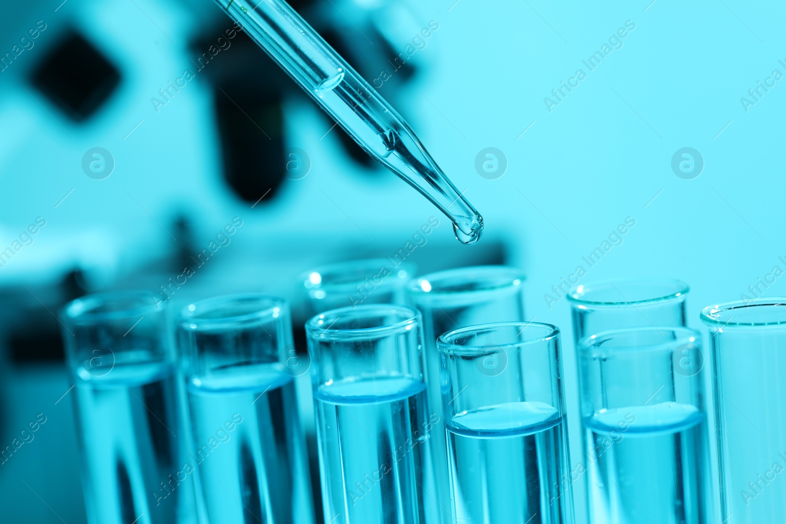 Photo of Dripping liquid from pipette into test tube on blurred background, closeup. Laboratory analysis