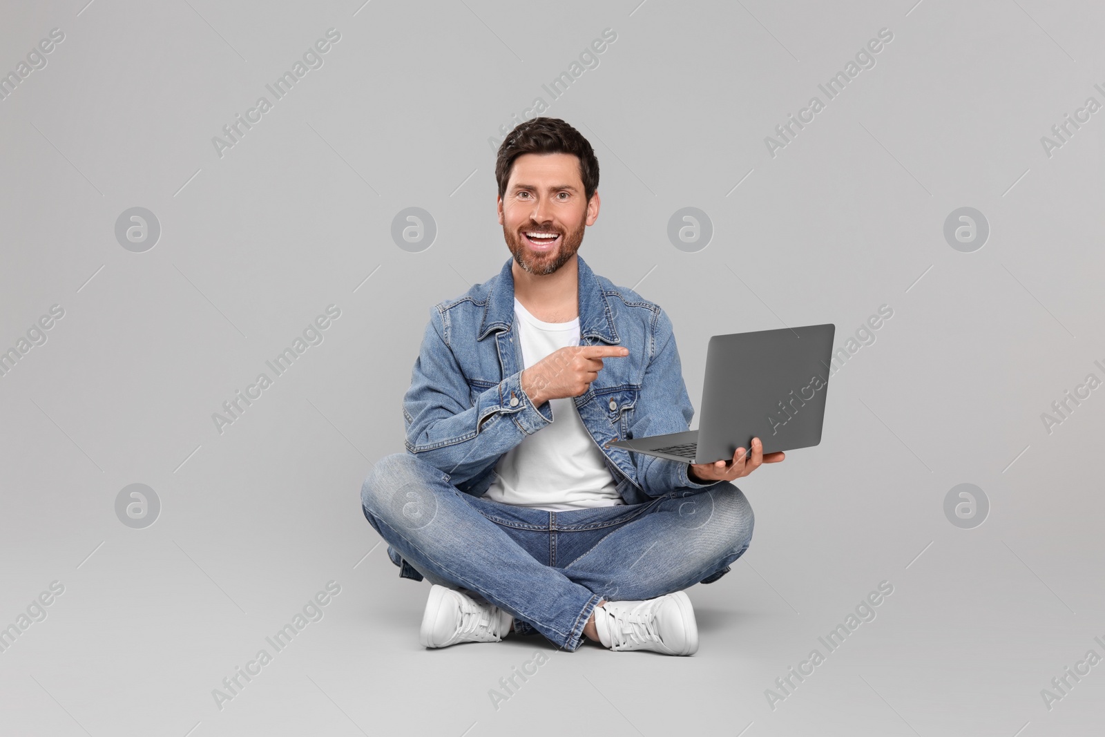 Photo of Happy man with laptop on light grey background