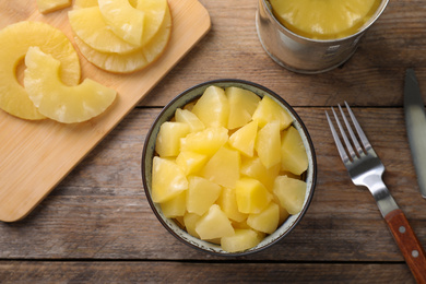 Photo of Flat lay composition with canned pineapple on wooden table