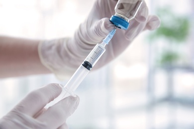 Photo of Doctor with syringe and medicine for vaccination on blurred background