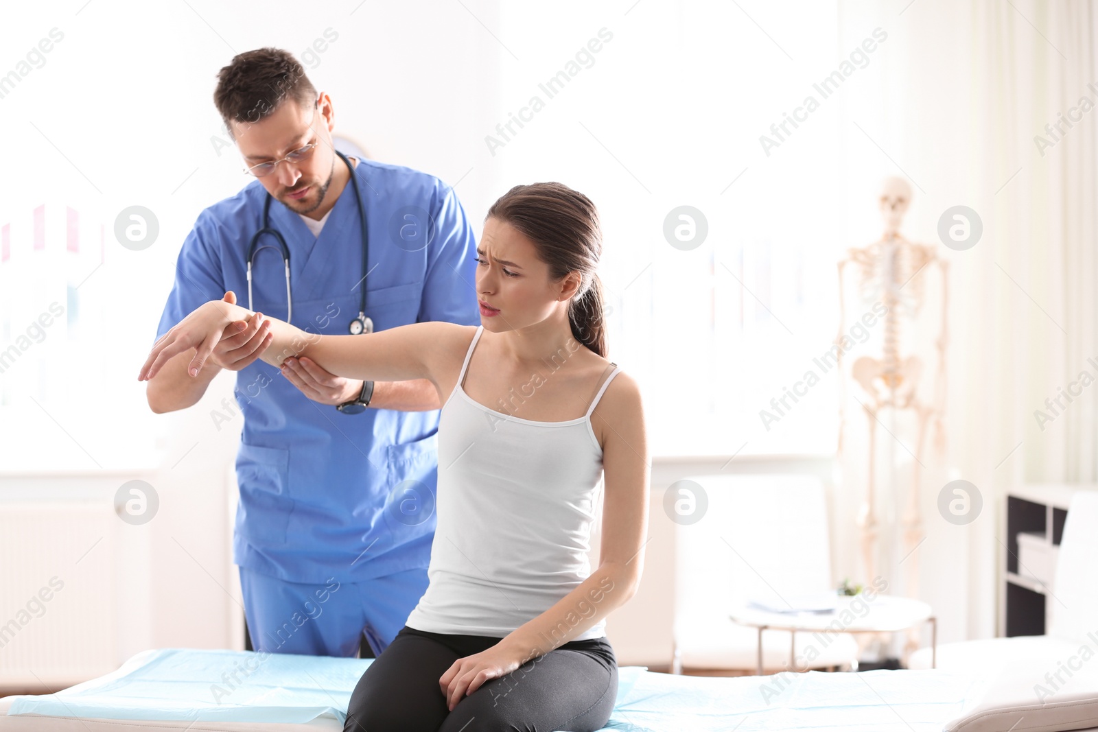 Photo of Male orthopedist examining patient's arm in clinic