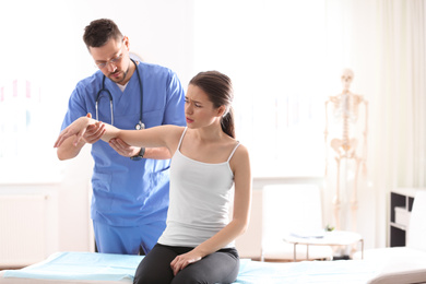 Male orthopedist examining patient's arm in clinic