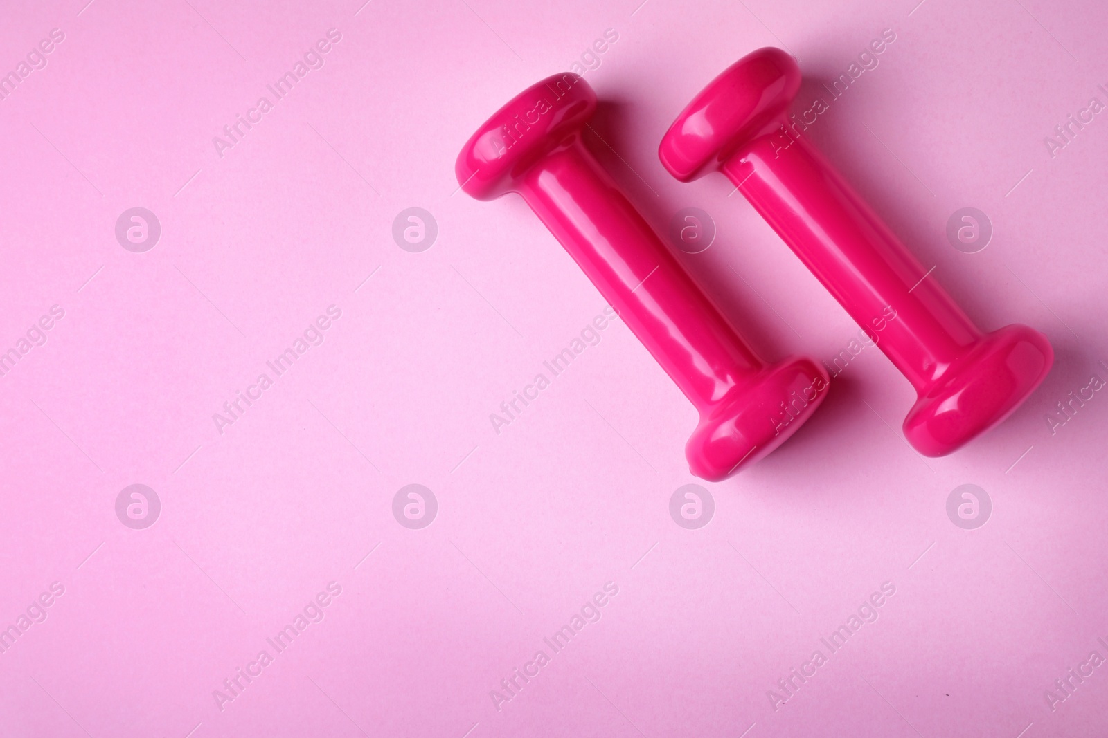 Photo of Bright dumbbells and space for text on color background, flat lay. Home fitness