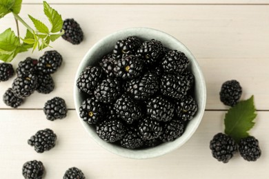 Photo of Fresh ripe blackberries on white wooden table, flat lay