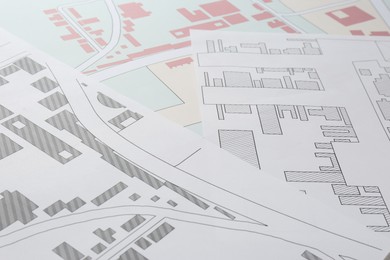 Many different cadastral maps of territory with buildings as background, closeup