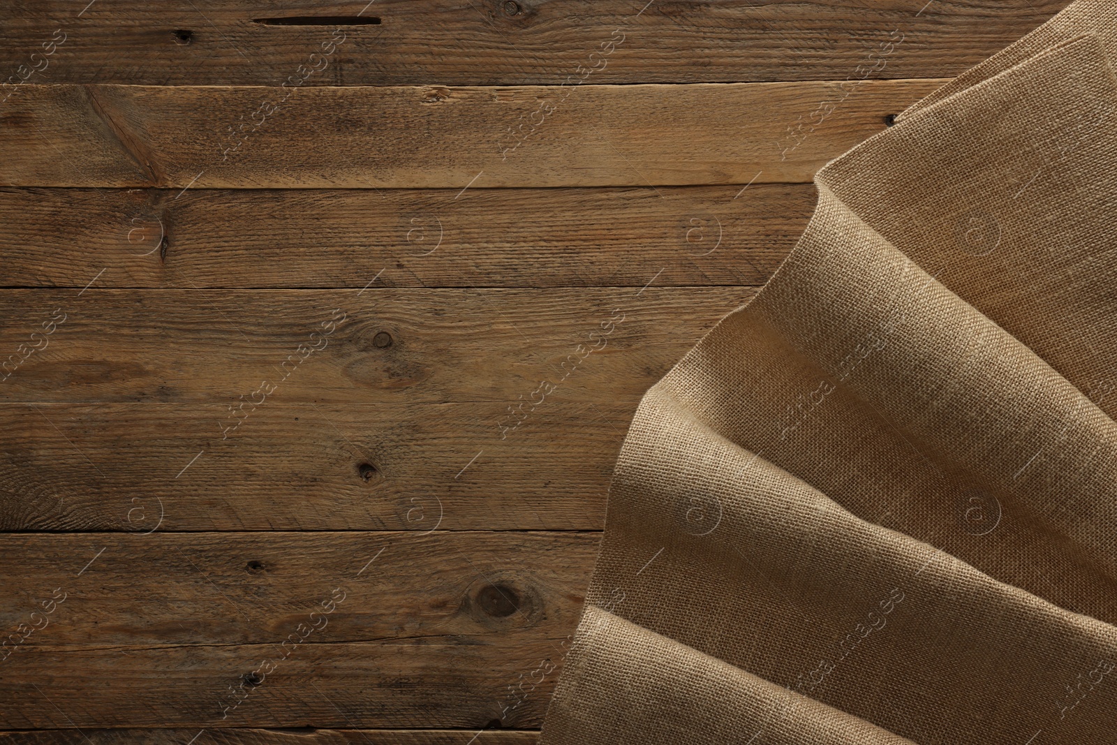 Photo of Burlap fabric on wooden table, top view. Space for text