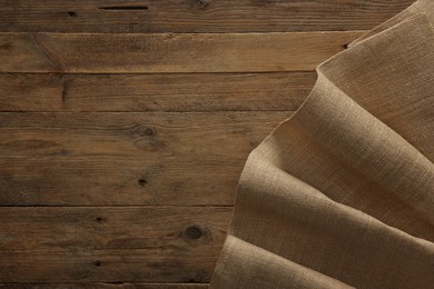 Photo of Burlap fabric on wooden table, top view. Space for text