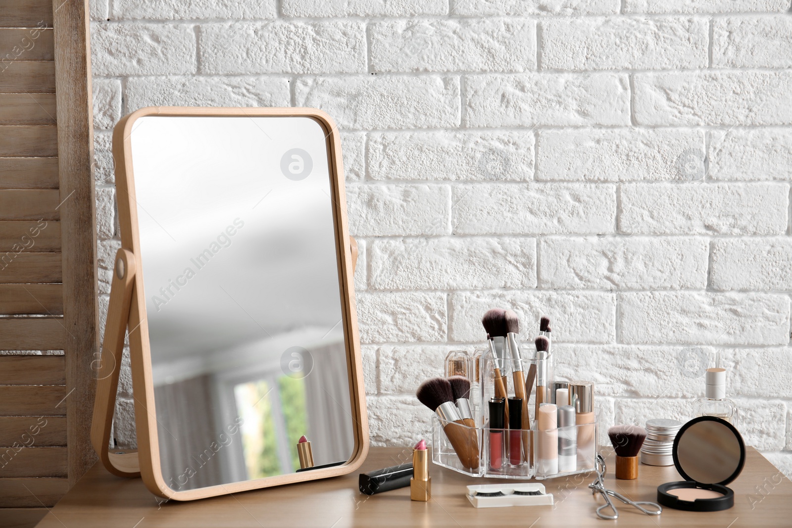 Photo of Makeup cosmetic products and tools on dressing table near brick wall with space for text