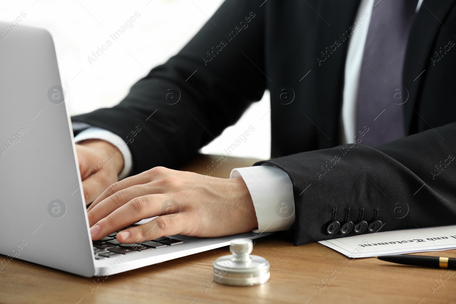 Photo of Male notary working with laptop at table, closeup