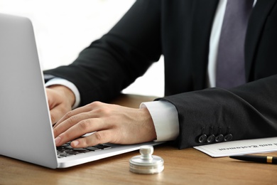 Male notary working with laptop at table, closeup