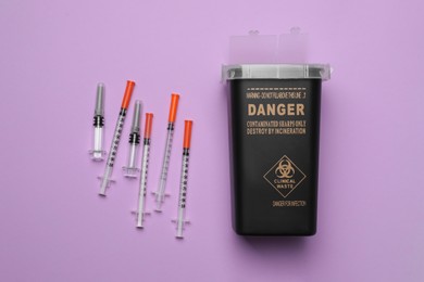 Photo of Disposable syringes and sharps container on violet background, flat lay