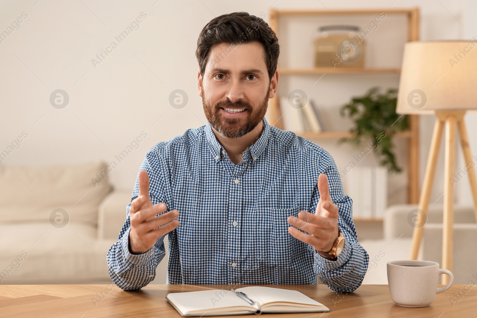 Photo of Happy man using video chat at wooden desk indoors, view from web camera