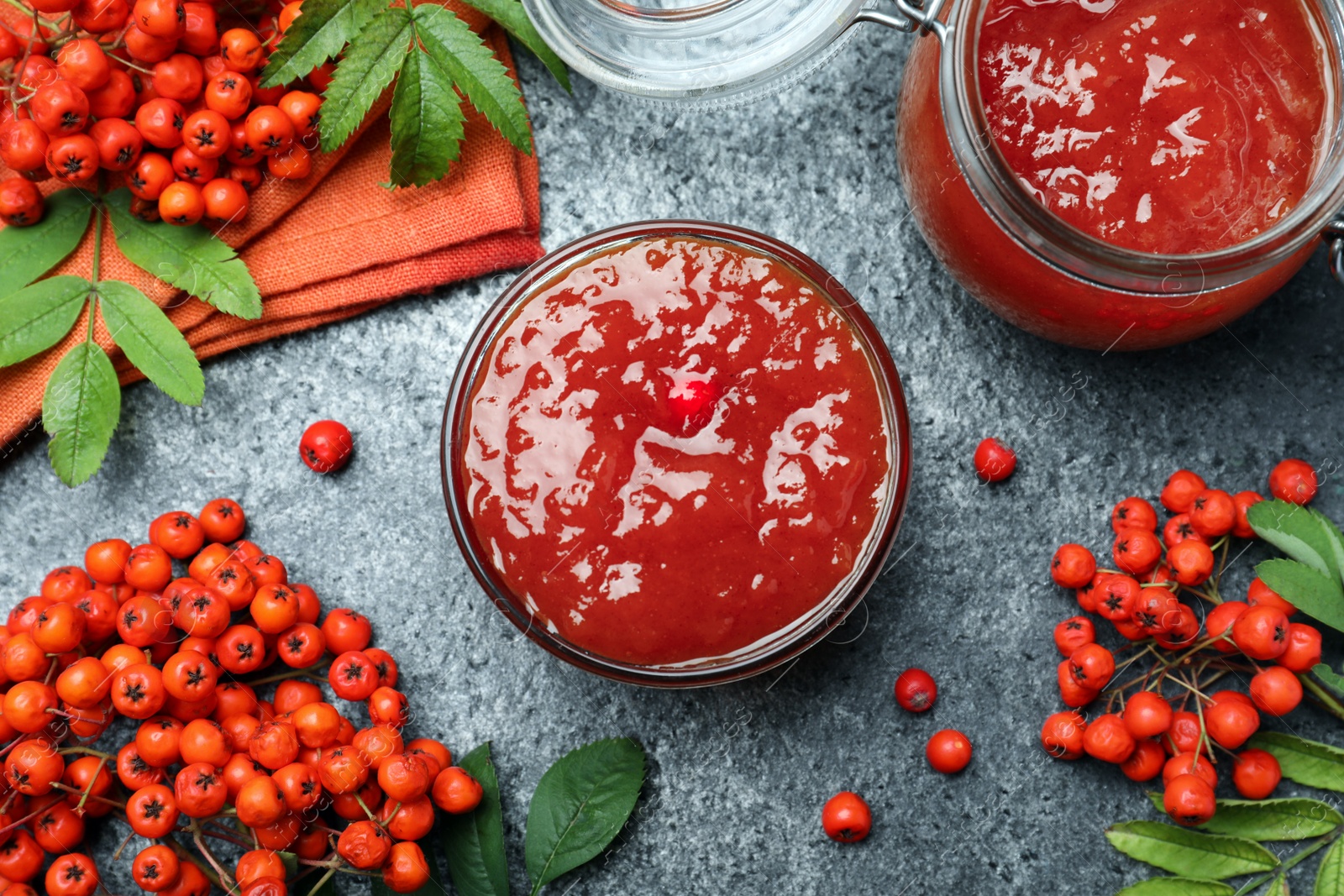 Photo of Flat lay composition with delicious rowan jam and berries on grey table