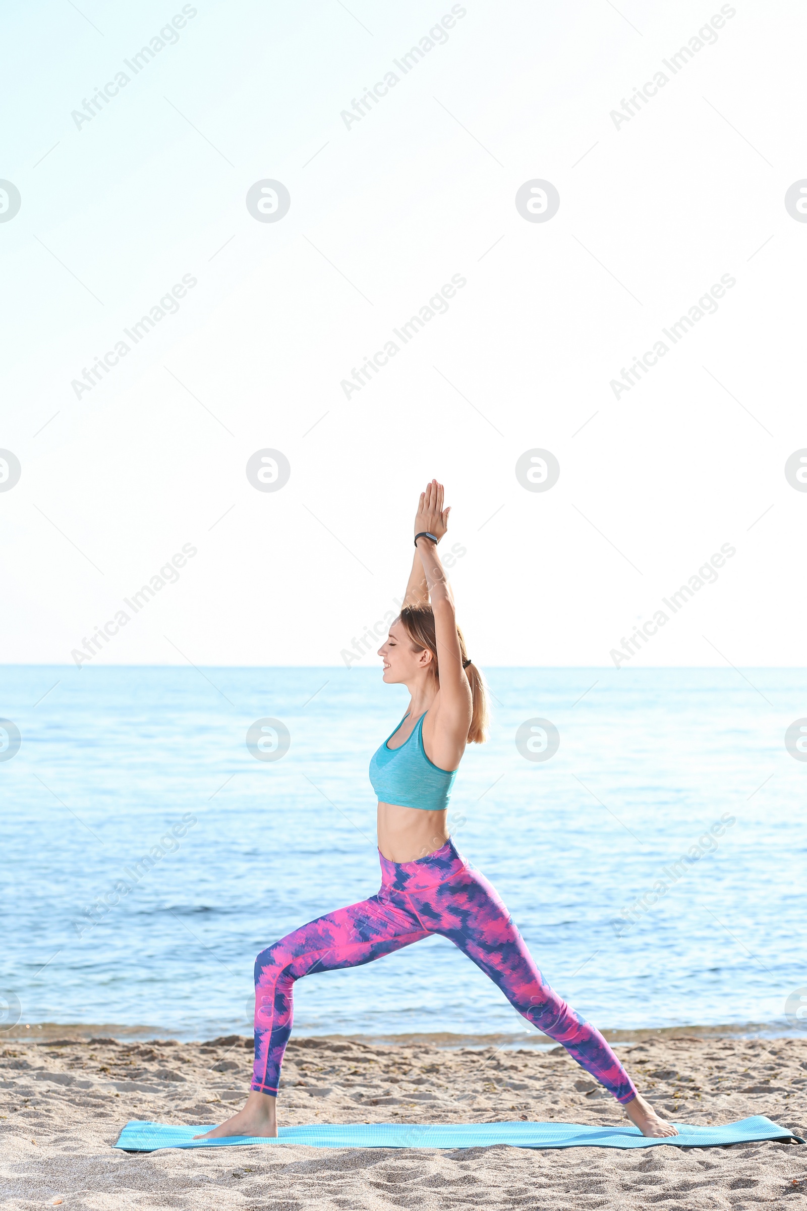 Photo of Young woman doing yoga exercises on beach in morning