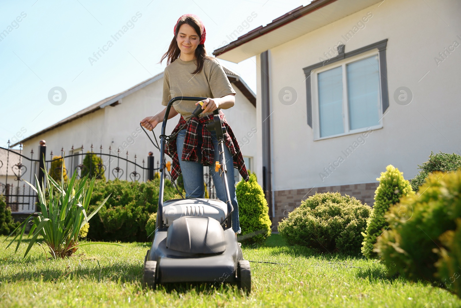 Photo of Smiling woman with modern lawn mower in garden