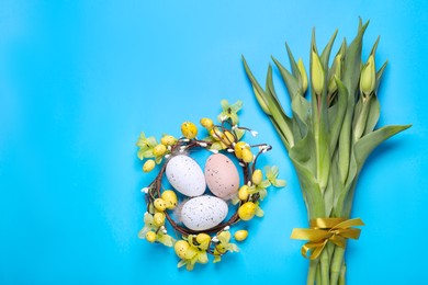 Flat lay composition with flowers and eggs on light blue background, space for text. Easter celebration