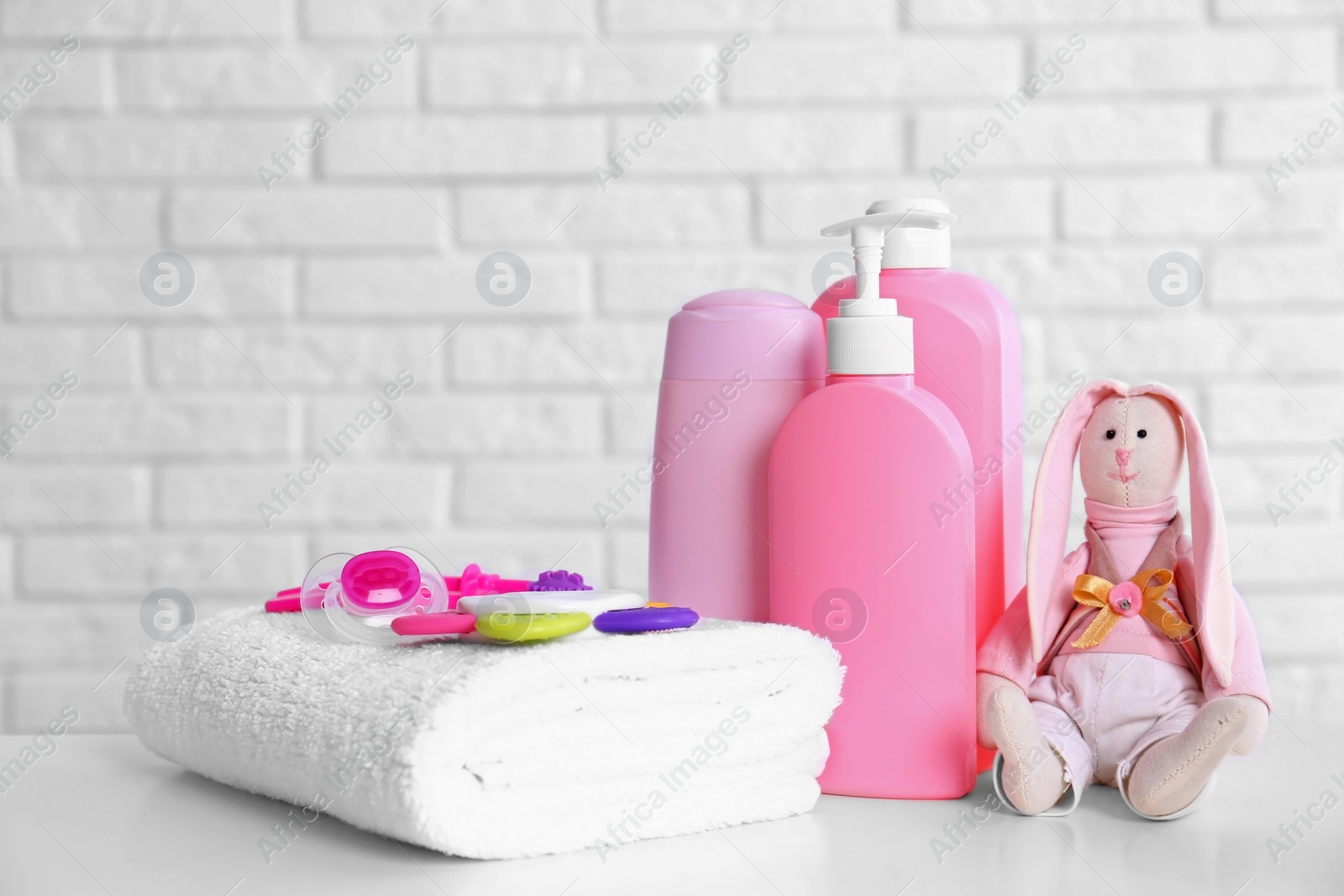 Photo of Baby accessories on table near white brick wall. Space for text