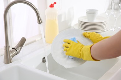 Photo of Woman washing plate in modern kitchen, closeup