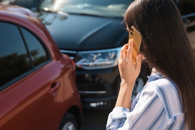 Photo of Young woman talking on phone after car accident outdoors, closeup
