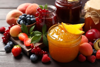 Photo of Jars with different jams and fresh fruits on wooden table, closeup